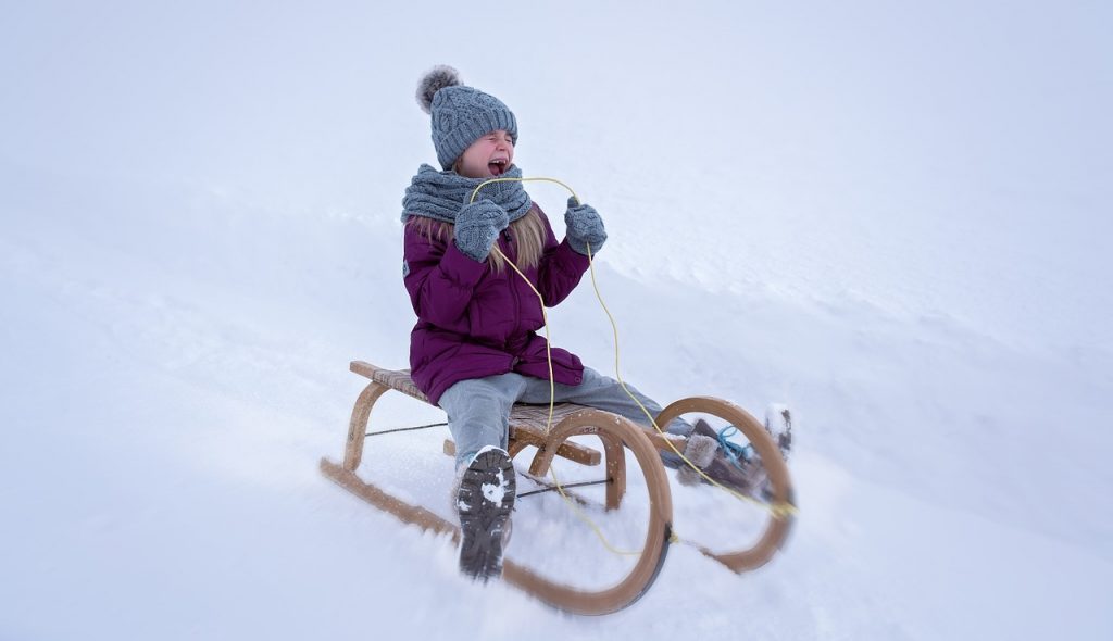 girl-sledding-down-hill